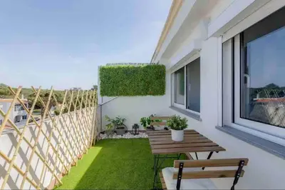 a balcony with a wooden table and a small yard at Cozy studio near the beach in Quarteira