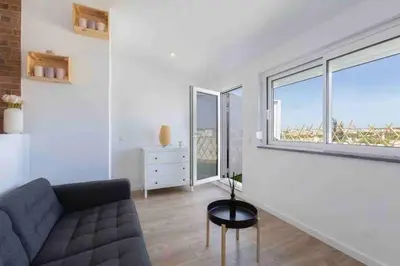a living room with a couch and a large window at Cozy studio near the beach in Quarteira
