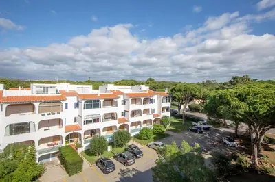 an apartment building with cars parked in a parking lot at Cozy studio near the beach in Quarteira