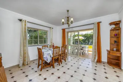 a dining room with a table and chairs and windows at Villa Casa Lourenco by Villa Plus in Albufeira
