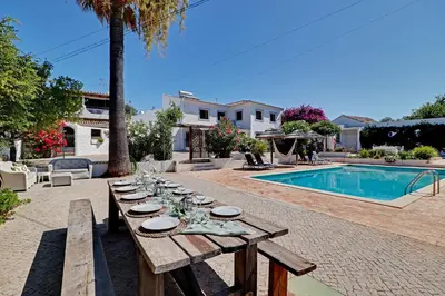 a wooden table with plates on it next to a pool at Quinta Boliqueime by Portucasa in Boliqueime