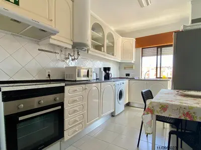 a kitchen with white appliances and a table with a tableablish at Blife Anya private rooms in Faro