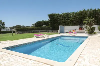 a swimming pool in a yard with two lawn chairs at Villa Luis Gale by Villa Plus in Galé