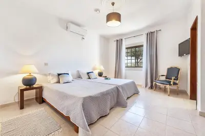 a white bedroom with a large bed and a chair at Loendros, Calma Moradia com Piscina Privada, Guia in Guia