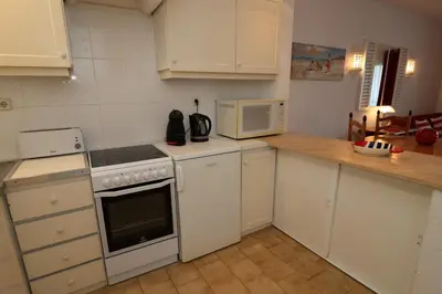 a kitchen with white cabinets and a stove and microwave at Studio Camélia 68 at São Rafael Beach - Albufeira in Albufeira
