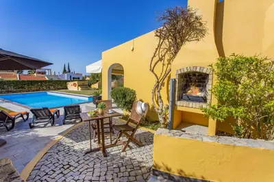 a yellow house with a table and chairs and a pool at Villa Tadeu Quatro by Villa Plus in Azinhal