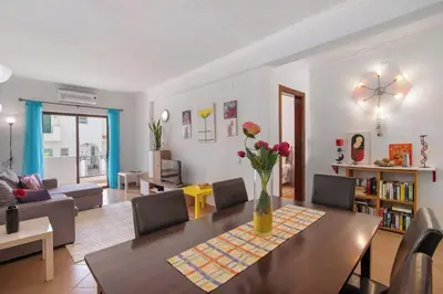 a living room with a table with a vase of flowers at Espaçoso apt T2, em Olhos Agua in Albufeira