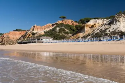 a beach with some rocks and the water at Espaçoso apt T2, em Olhos Agua in Albufeira