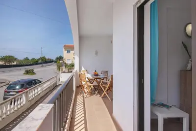 a balcony with a table and a car on a street at Espaçoso apt T2, em Olhos Agua in Albufeira
