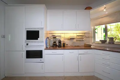 a white kitchen with white appliances and a window at Villa Pinheiro Manso in Albufeira