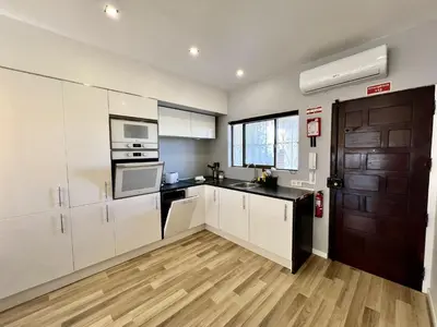 a kitchen with white cabinets and a wooden floor at Albufeira Central 7 by Homing in Albufeira