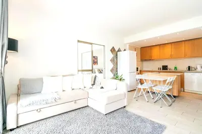 a living room with a white couch and a kitchen at Spacious 1 bed in Vilamoura, Fast Wifi & Pool in Quarteira