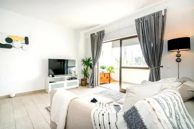 a white living room with a couch and a tv at Spacious 1 bed in Vilamoura, Fast Wifi & Pool in Quarteira