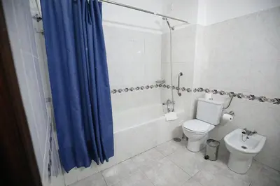 a bathroom with a toilet and a blue shower curtain at Apartamento T1 todo equipado in Albufeira