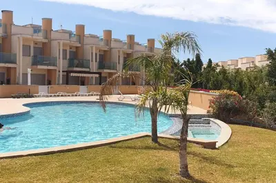 a palm tree in front of a building with a swimming pool at Casa Praia Patroves in Patroves