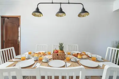 a dining room table with white chairs and fruit on it at HostWise - Spacious & Sunny Flat - Loulé in Loulé