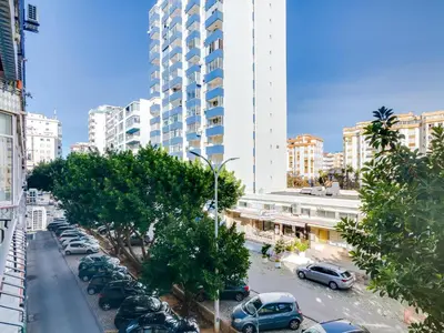 a street with cars parked in a city with tall buildings at AL - Beachside Hideaway Quarteira in Quarteira