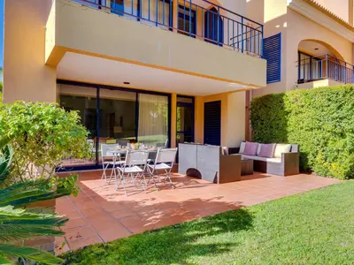 a patio with a table and chairs in front of a building at AL - Vila Sol Golfside Ground Floor in Vilamoura