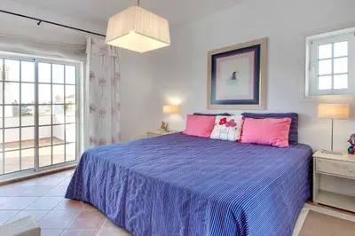 a bedroom with a blue bed with pink pillows at Villa Costa Rica in Galé
