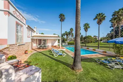 an exterior view of a house with a swimming pool and palm trees at Casa Lorena in Guia
