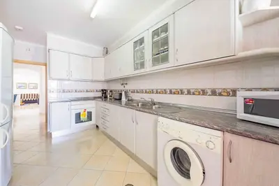 a kitchen with white cabinets and a washer and dryer at Villa Marco in Galé