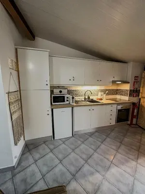 an empty kitchen with white cabinets and a sink at Estúdio em Alte - KARMEA HOUSES in Alte