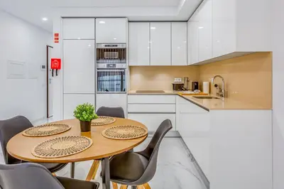 a kitchen with a wooden table and chairs at Sublime and Bright 2 BDR Apartment by LovelyStay in Quarteira
