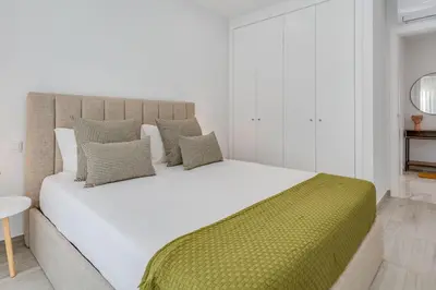 a bedroom with a large white bed with a green blanket at Sublime and Bright 2 BDR Apartment by LovelyStay in Quarteira