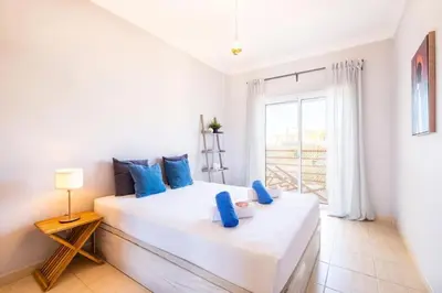 a bedroom with a large white bed with blue pillows at Solymar Apartment in Guia