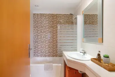 a bathroom with a sink and a tub and a mirror at Condomínio Quinta do Vale in Guia