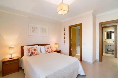 a bedroom with a bed and two lamps and a bathroom at Condomínio Quinta do Vale in Guia