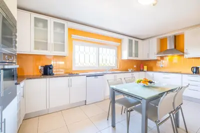 a kitchen with white cabinets and a table with chairs at Villa Eagles Nest by Algarve Vacation in Albufeira