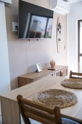 a dining room with a table with a television on the wall at Gyula Old Town Apartment in Albufeira