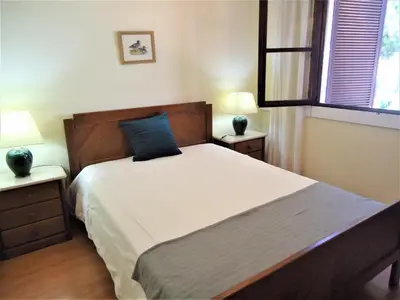 a bedroom with a bed with a blue pillow on it at V2 Vilar Jardim Piscina wifi in Quarteira