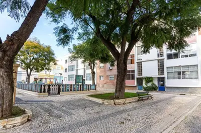 a park with trees and a bench and buildings at Blife Farensya private rooms near train station in Faro