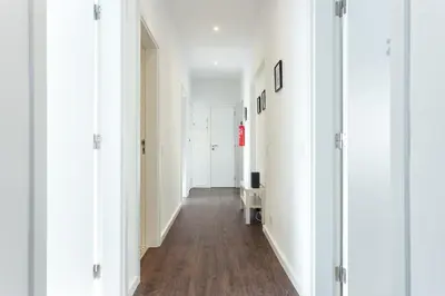 an empty hallway with white walls and wood floors at Blife Farensya private rooms near train station in Faro