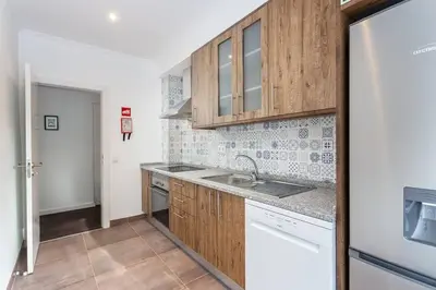 a kitchen with wooden cabinets and a sink at Blife Farensya private rooms near train station in Faro