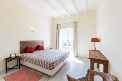 a white bedroom with a bed and a window at Villa Ataboeira in Guia