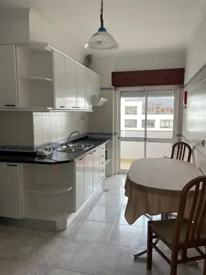 a kitchen with white cabinets and a table and a dining room at STUDIO COMPLETO PARA 2 PESSOAS in Albufeira