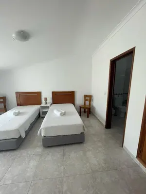 a bedroom with two beds and a bathroom with a mirror at STUDIO COMPLETO PARA 2 PESSOAS in Albufeira