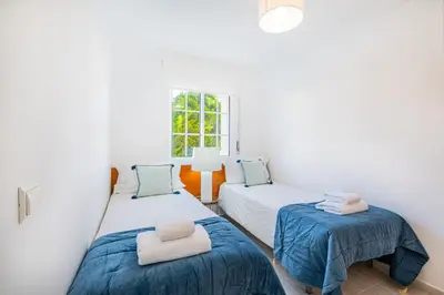two twin beds in a white room with blue sheets at Notre Damme Apartment in Albufeira
