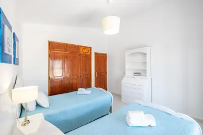 a bedroom with two beds and a lamp and a dresser at Villa Guerreiro in Albufeira