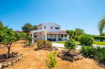 a large white house with trees in the yard at Villa Guerreiro in Albufeira