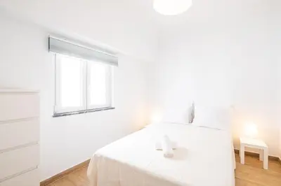 a white bedroom with a bed and a window at SERAFIM BEACH APARTMENT - Heart of the Old Town in Albufeira