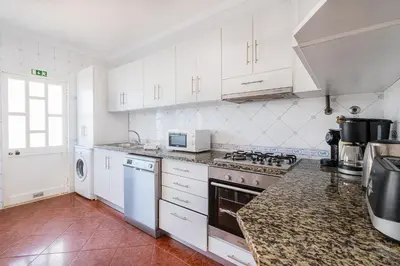 a kitchen with white cabinets and a stove top oven at Villa Melissa in Albufeira