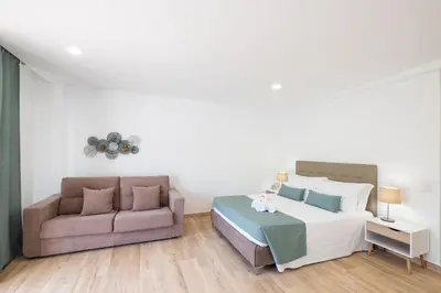a bedroom with a bed and a couch at Studio Guerreiro in Albufeira