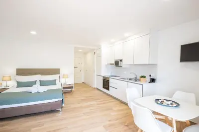 a bedroom with a bed and a kitchen with a table at Studio Guerreiro in Albufeira