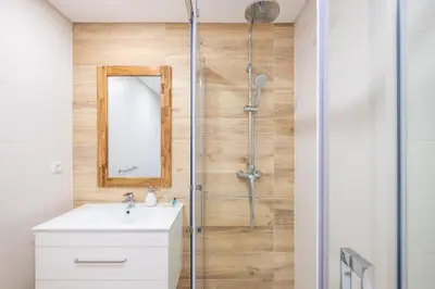 a bathroom with a shower with a sink and a mirror at Studio Guerreiro in Albufeira