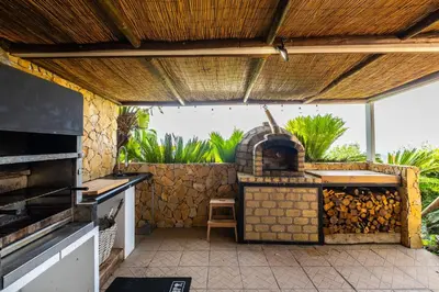 an outdoor kitchen with an outdoor pizza oven at Casa Picota in Boliqueime