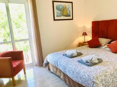 a bedroom with a bed and a chair and a window at Charming 3 bed apartment @ Al-Sakia Village in Quarteira